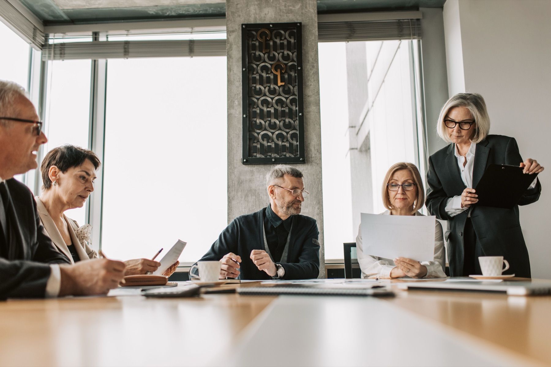 Company directors reviewing documents in a boardroom meeting