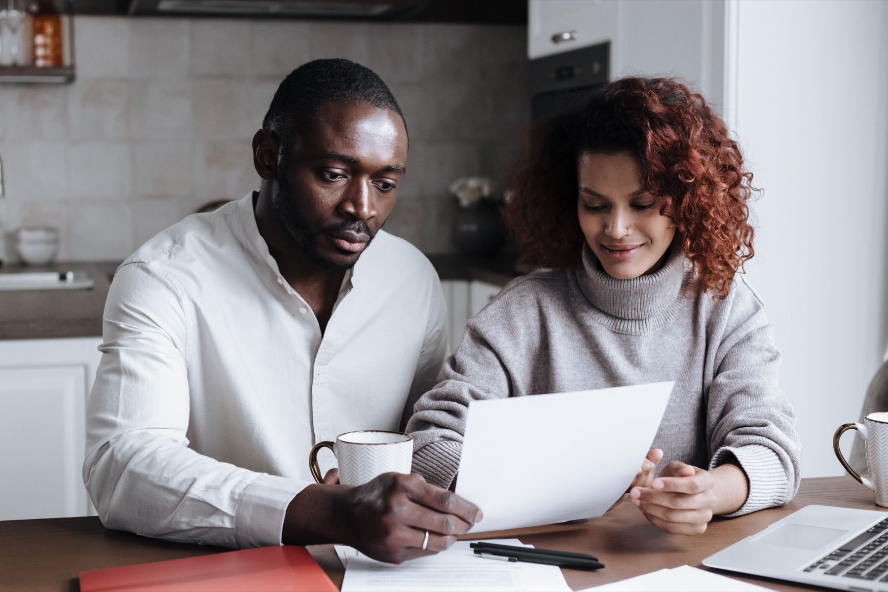 Couple reviewing property paperwork together at a kitchen table